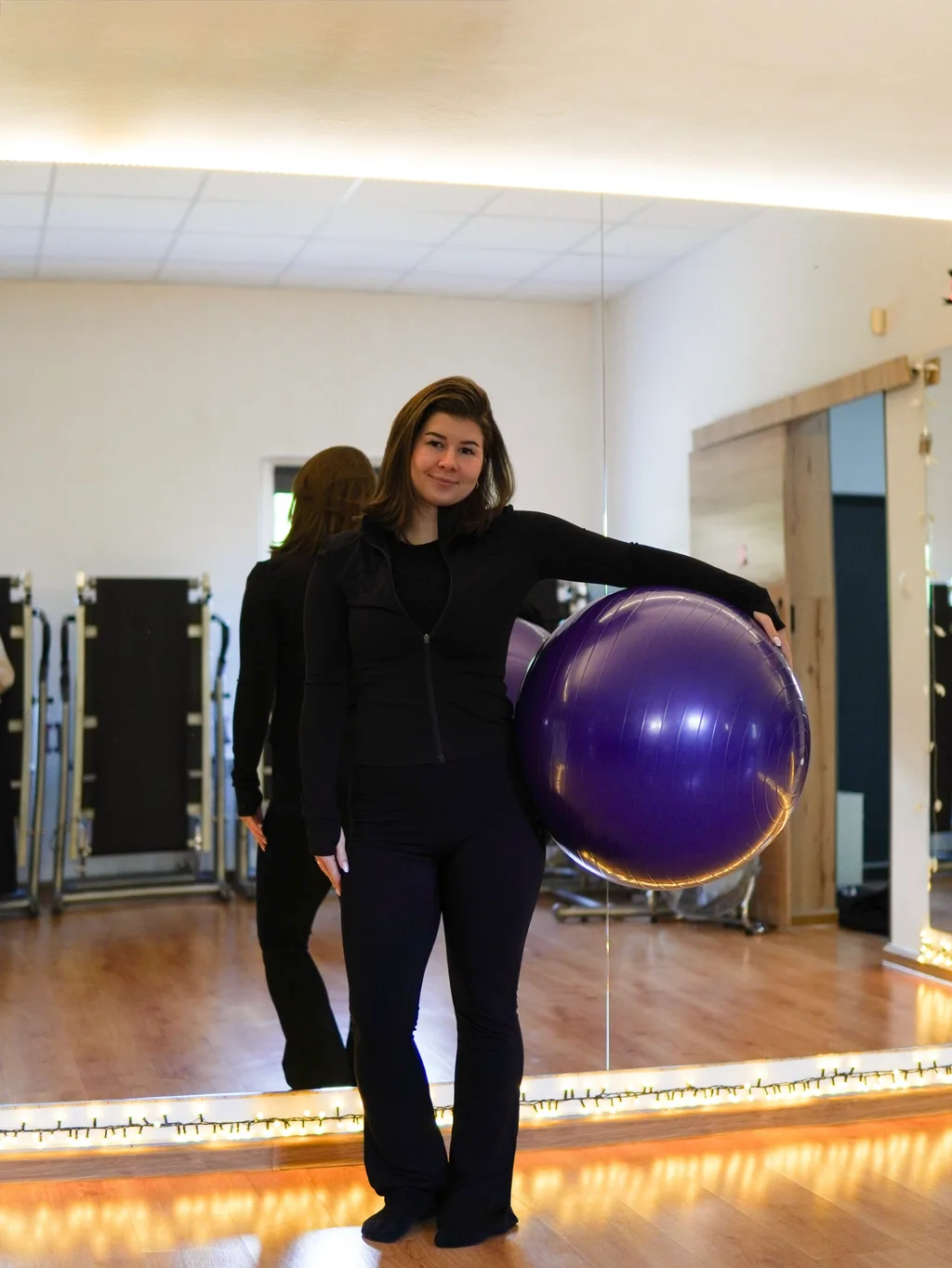 Trenerka ME Studio z piłką gimnastyczną na sali treningowej